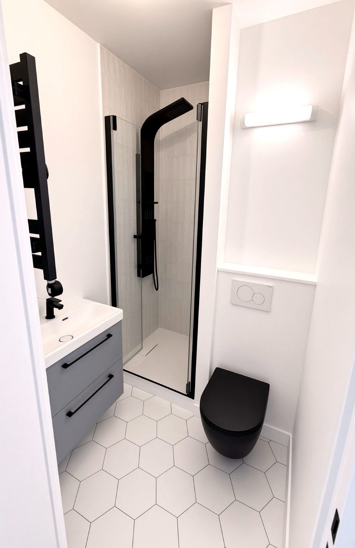 Salle d’eau compacte, douche noire, WC suspendu noir, carrelage hexagone